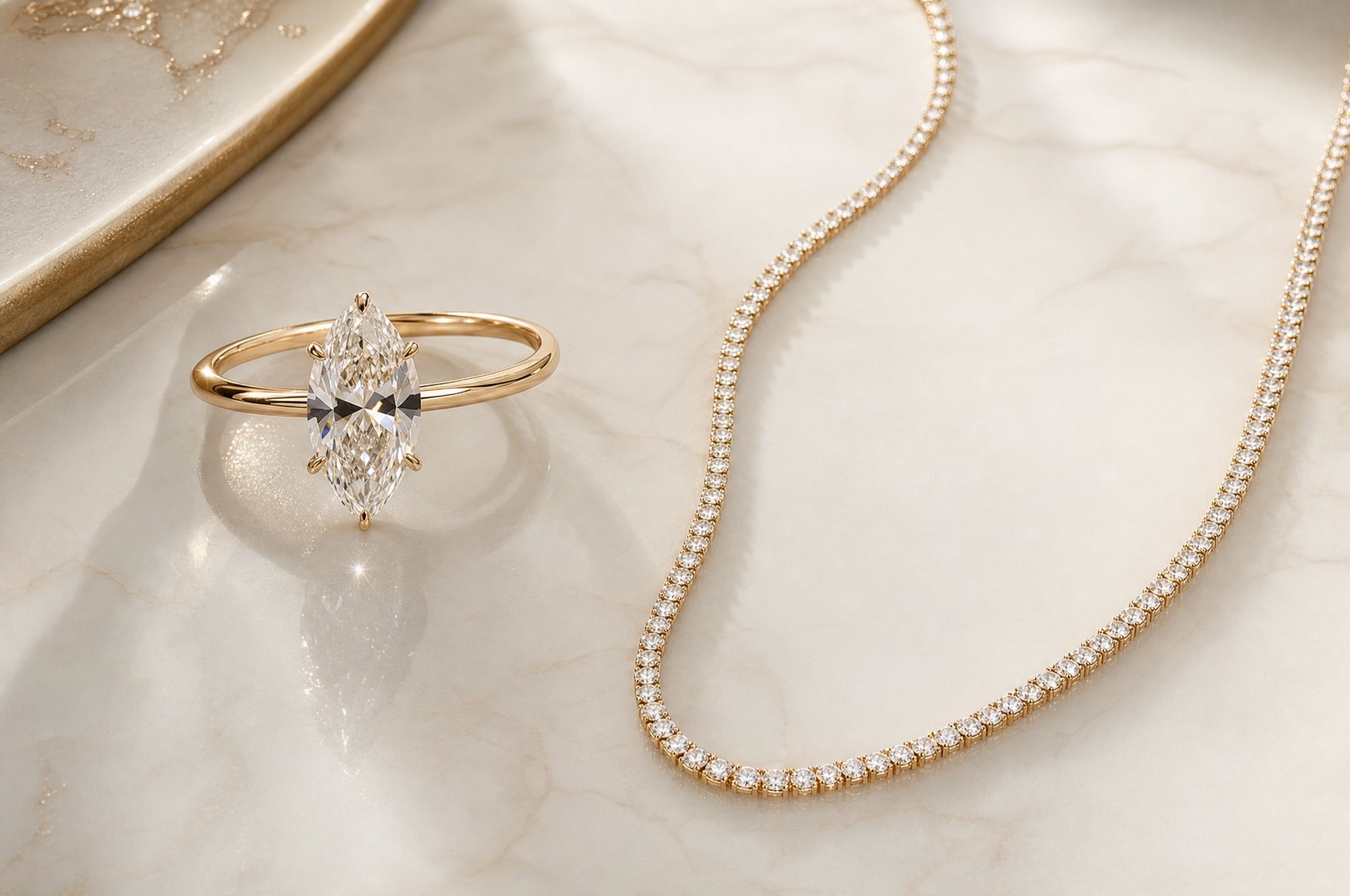 A marquise-cut solitaire in yellow gold beside a diamond line necklace, on cream marble
